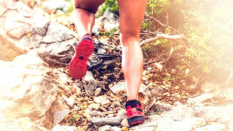 the legs of a woman scrambling up rough terrain