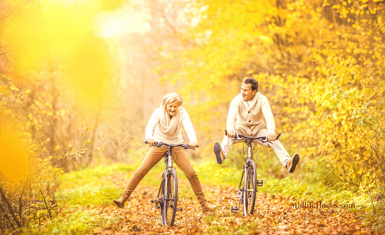 Mature couple cycling through wood in the fall