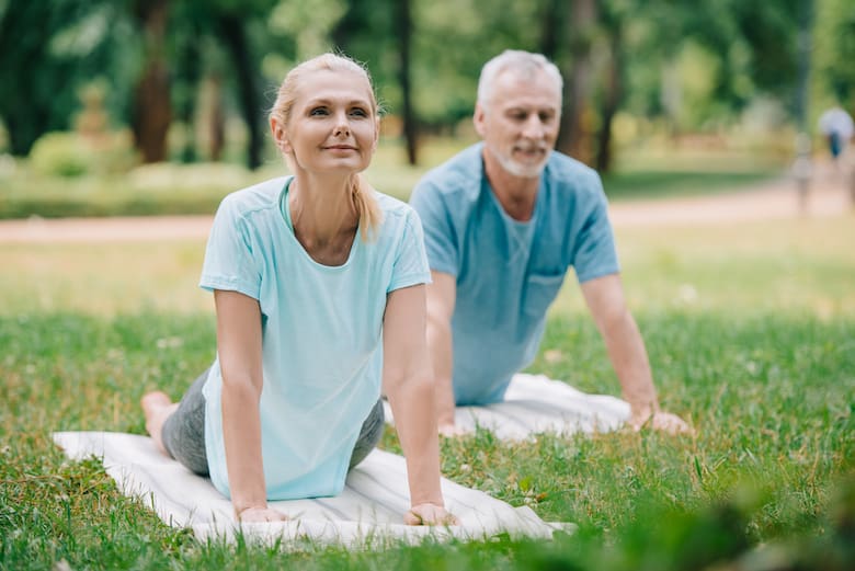 midlife couple holding a cobra in a park