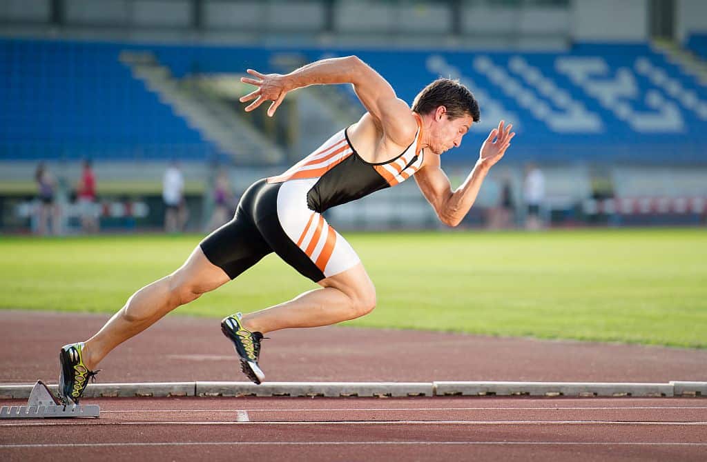 Sprinter leaving starting blocks on the running track. The best compression tops are those that are compression bottoms too.