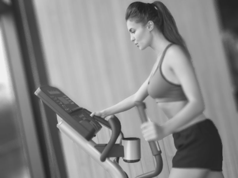 A blurred young girl on an elliptical trainer at home