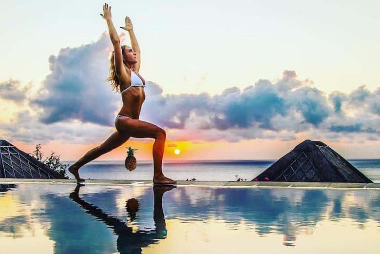 bikini girl at sunset sea background doing effective vagina weightlifting with what looks to be a pineapple