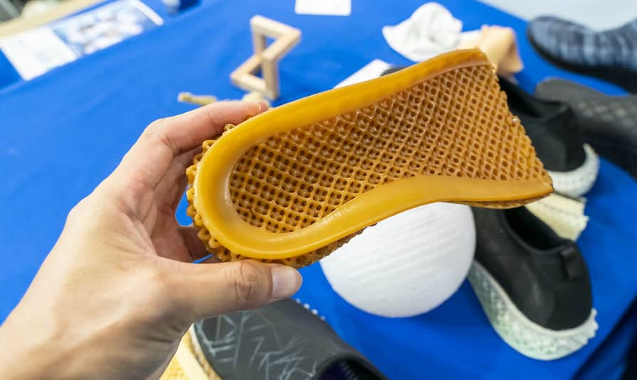 hand with 3d printed shoe figure close-up - hard to recycle running shoes
