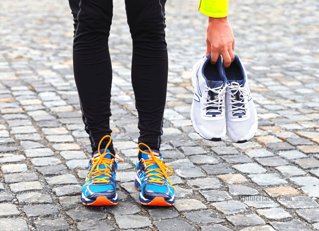 Lower legs wearing running shoes and hand holding a pair